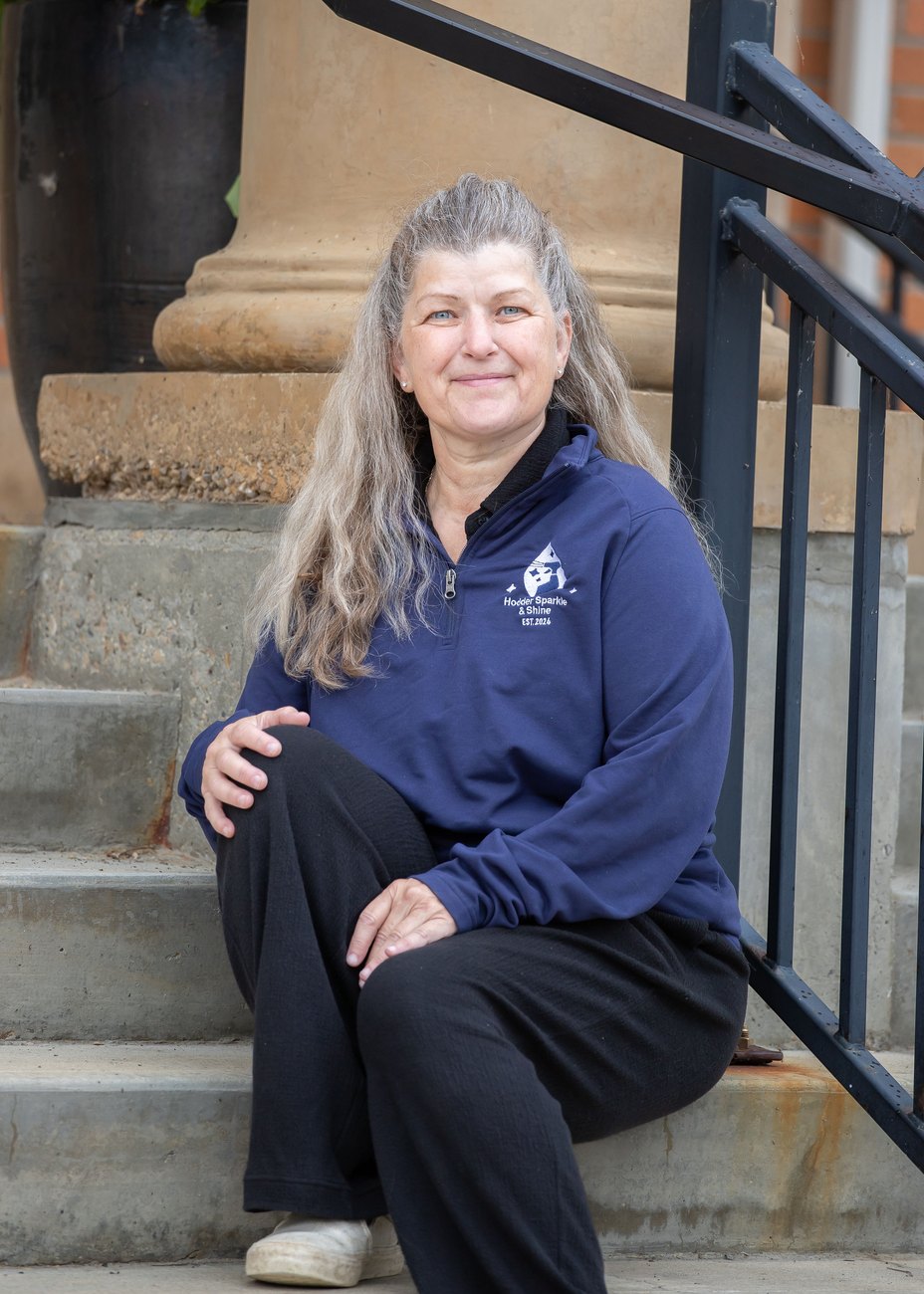 Christina, Hodder Sparkle & Shine cleaner, sitting on steps in her HSS quarter-zip
